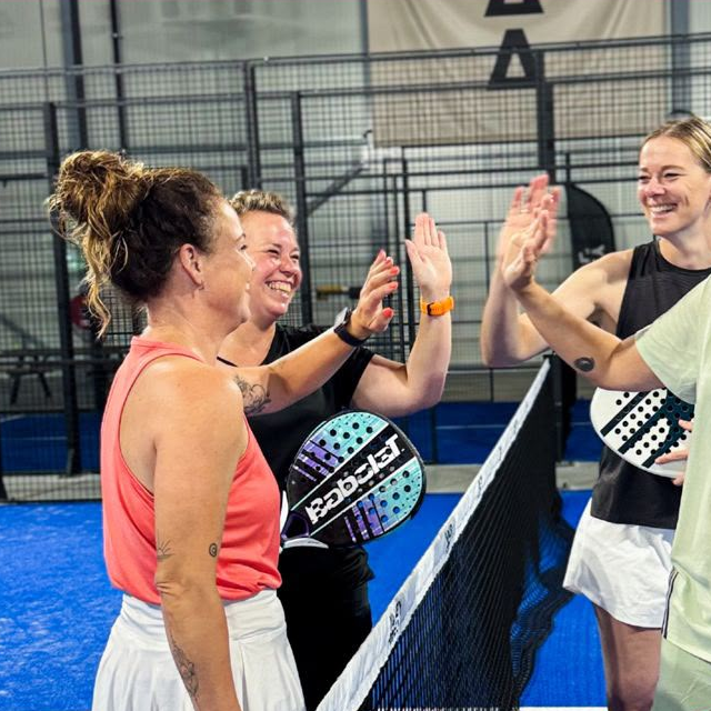 Padelspelers geven elkaar een high five op de baan